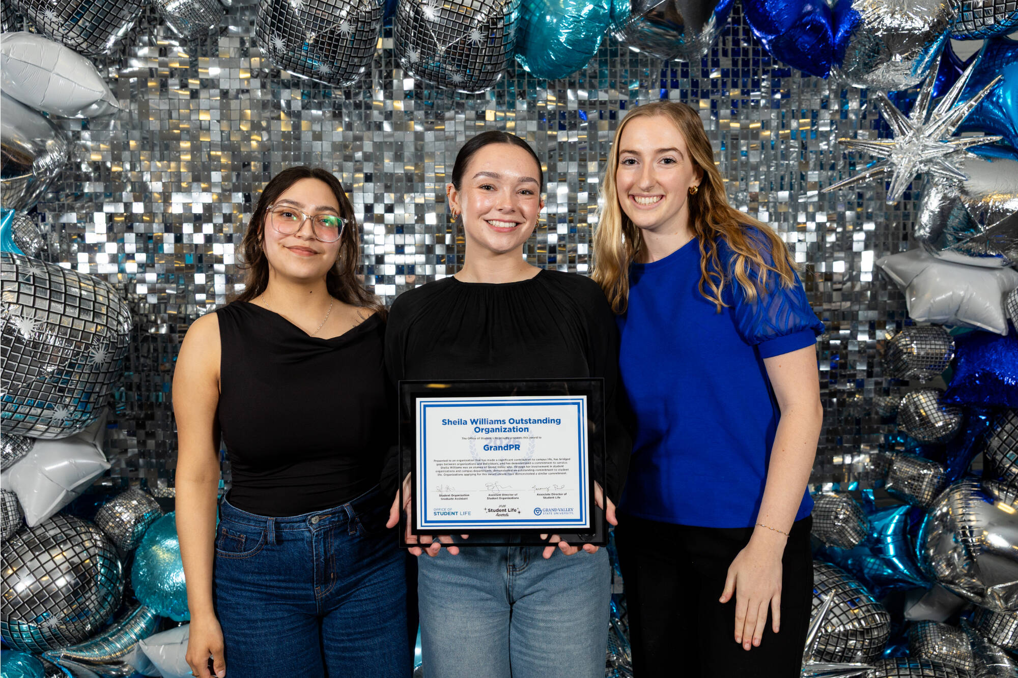 Three individuals holding an award certificate